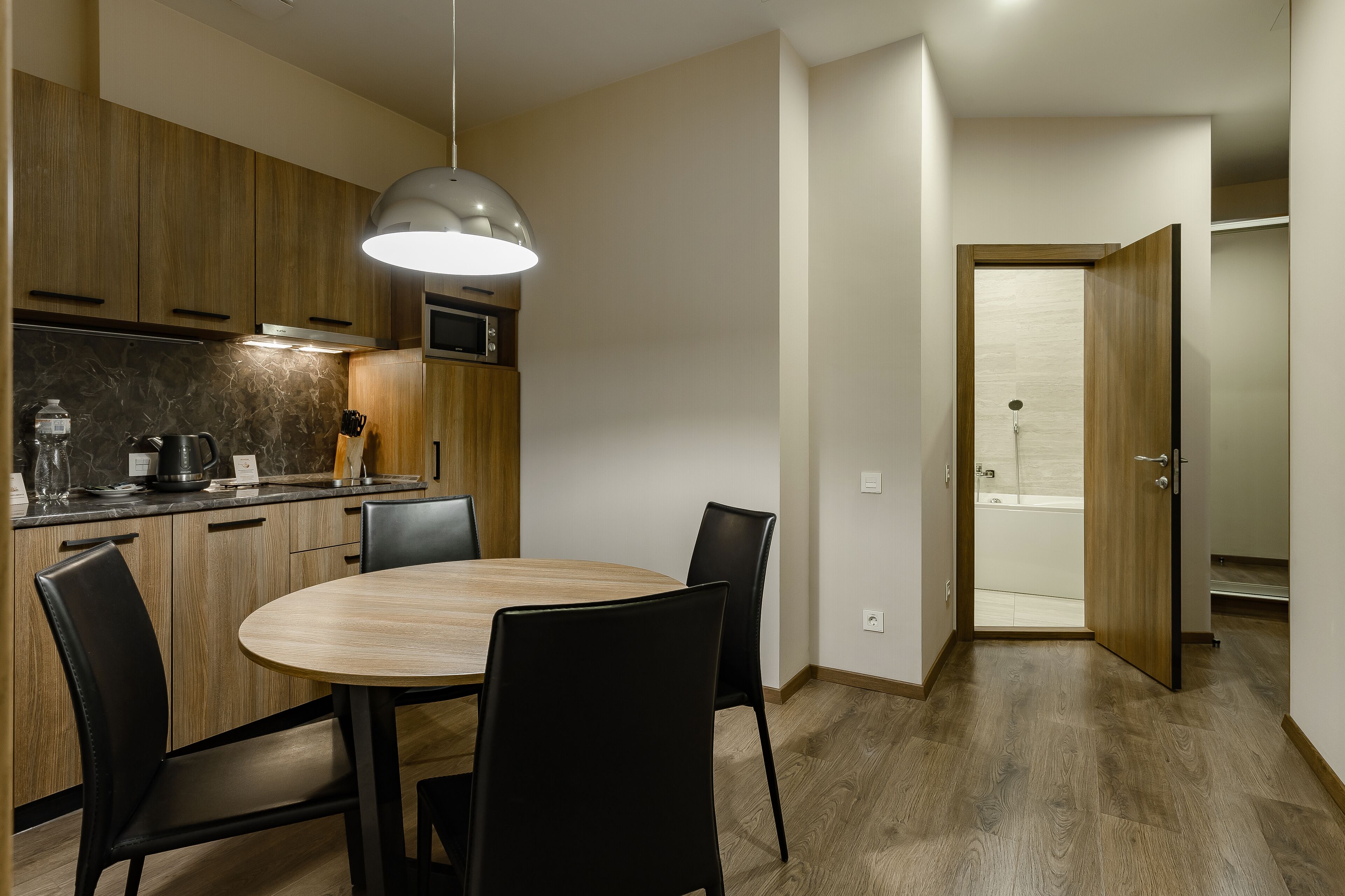 A modern kitchen with wooden cabinets, a round dining table, and black chairs.