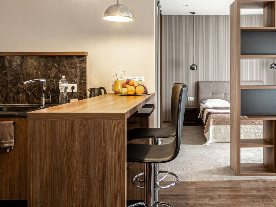 A modern kitchen with wooden cabinets, a marble backsplash, and a wooden island with bar stools.