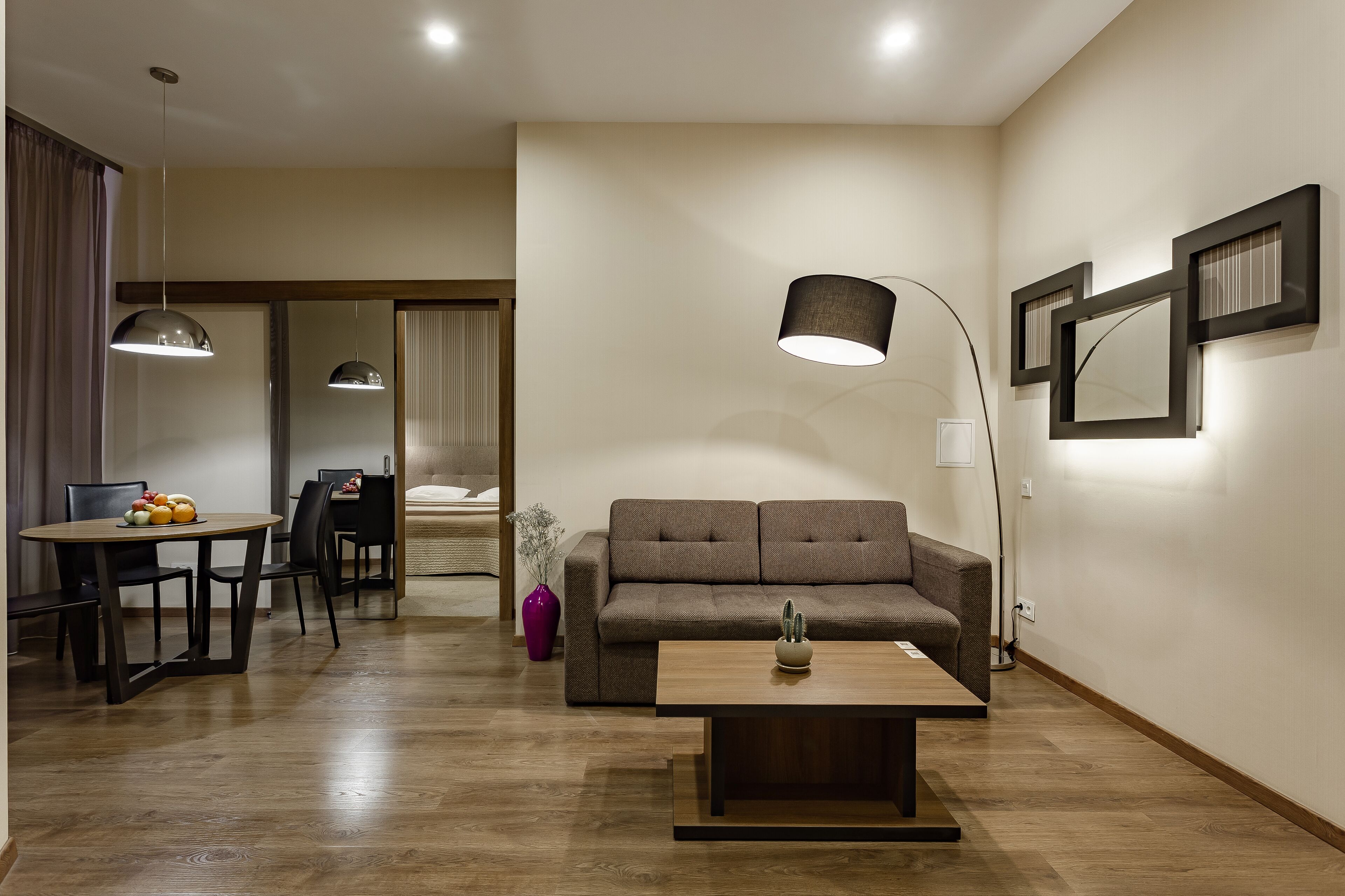 Un salon moderne comprenant un canapé, une table basse, une table à manger et des luminaires suspendus.
