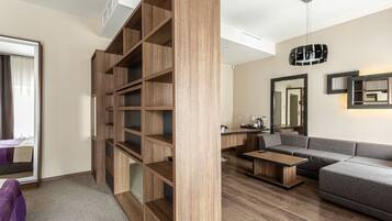 A modern living room with a wooden bookshelf, a grey sofa, a coffee table, and a desk with a chair.