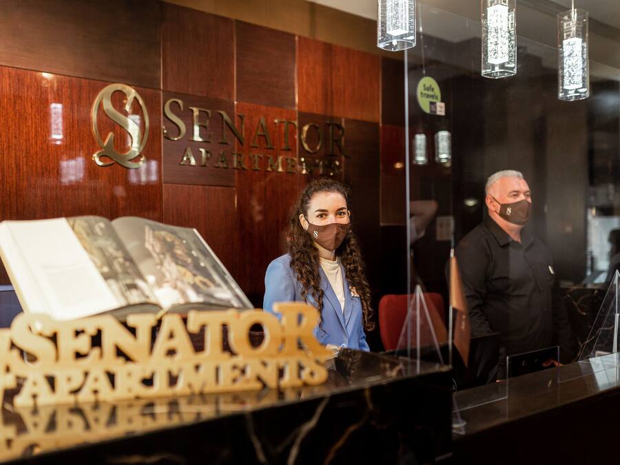 Una recepción con un panel de madera y un letrero que dice 'SENATOR APARTMENTS'.