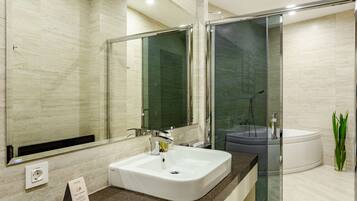 A modern bathroom with a large mirror, a white sink, a glass-enclosed shower, and a bathtub.