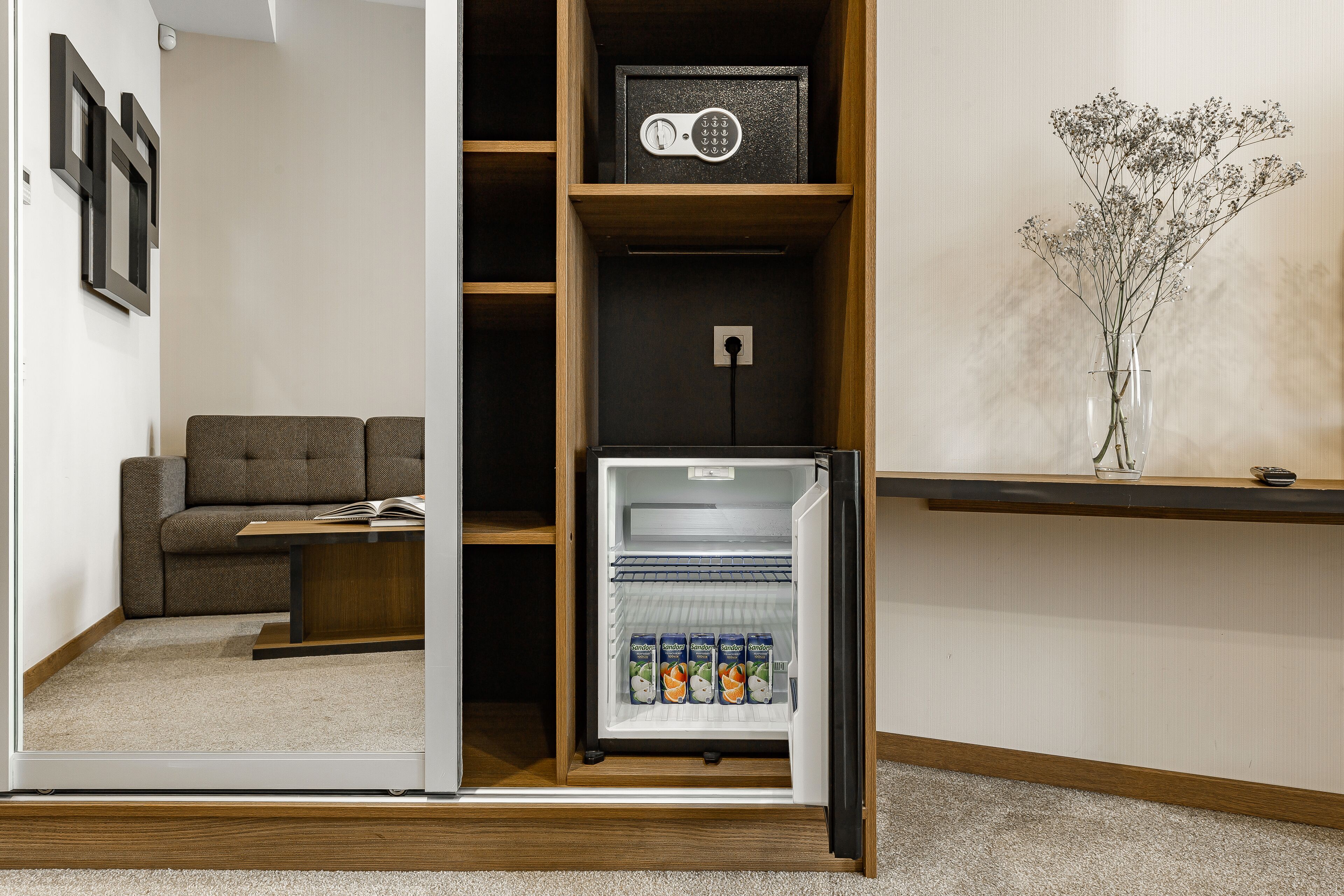 A compact living space with a built-in refrigerator, a sofa, and a small table.
