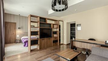 Una sala de estar moderna con televisión, muebles de madera, un sofá y un comedor.