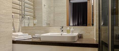A modern bathroom with a white sink, a glass shower enclosure, and a toilet.