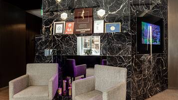A lobby with marble walls, framed awards, a television, and seating.