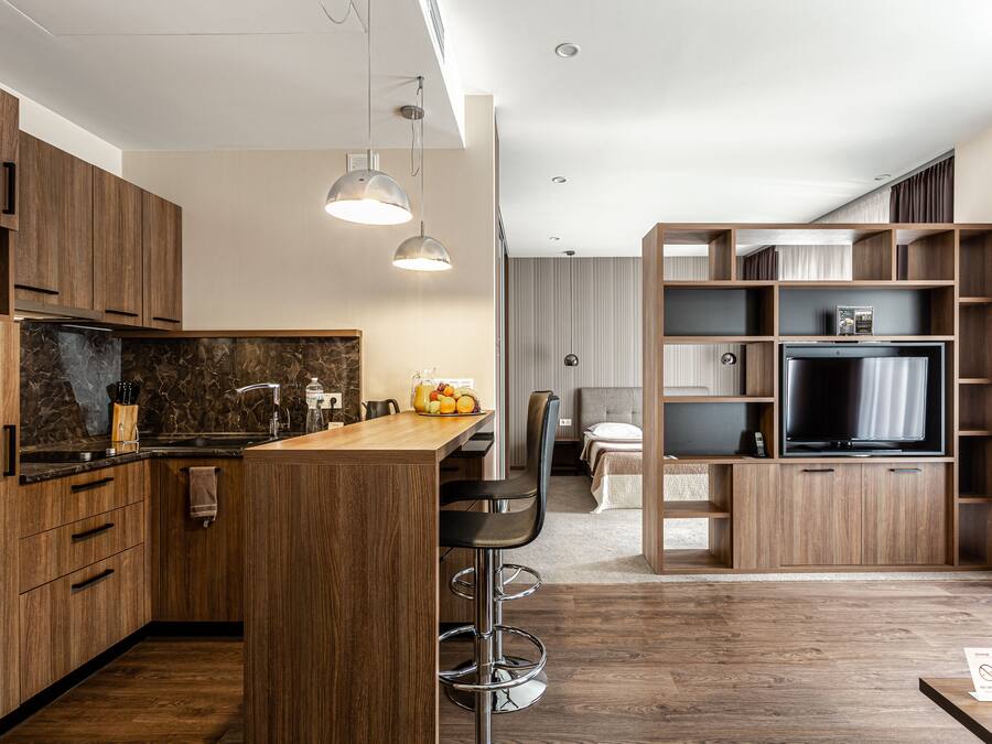 Una cocina moderna con armarios de madera, salpicadero de mármol y una isla central con taburetes de bar.