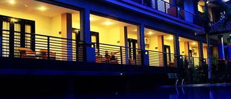 Un hotel de varios pisos con balcones, piscina e iluminación cálida.