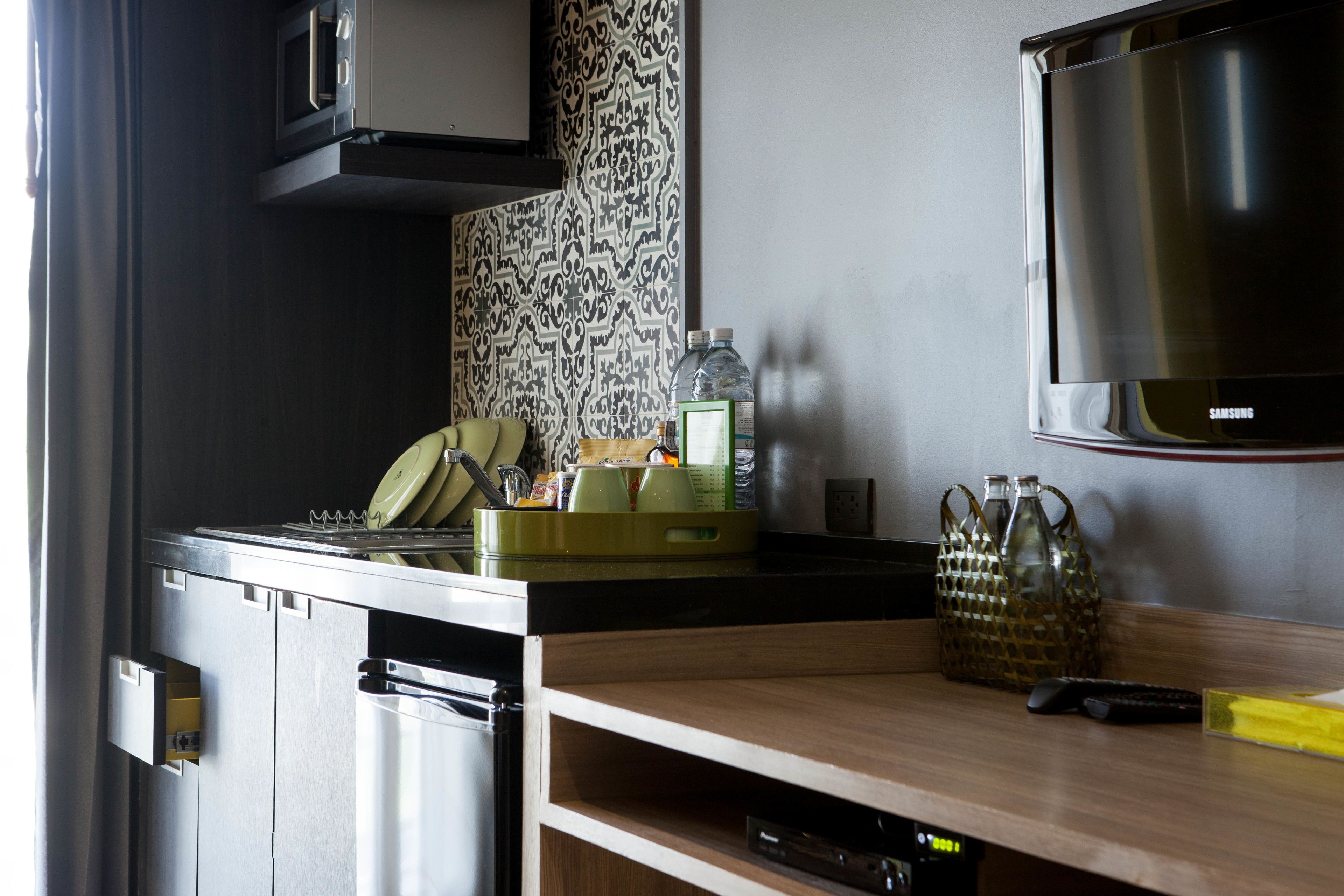 Une cuisine moderne équipée d’un four à micro-ondes, d’une cuisinière et d’un téléviseur fixé au mur.