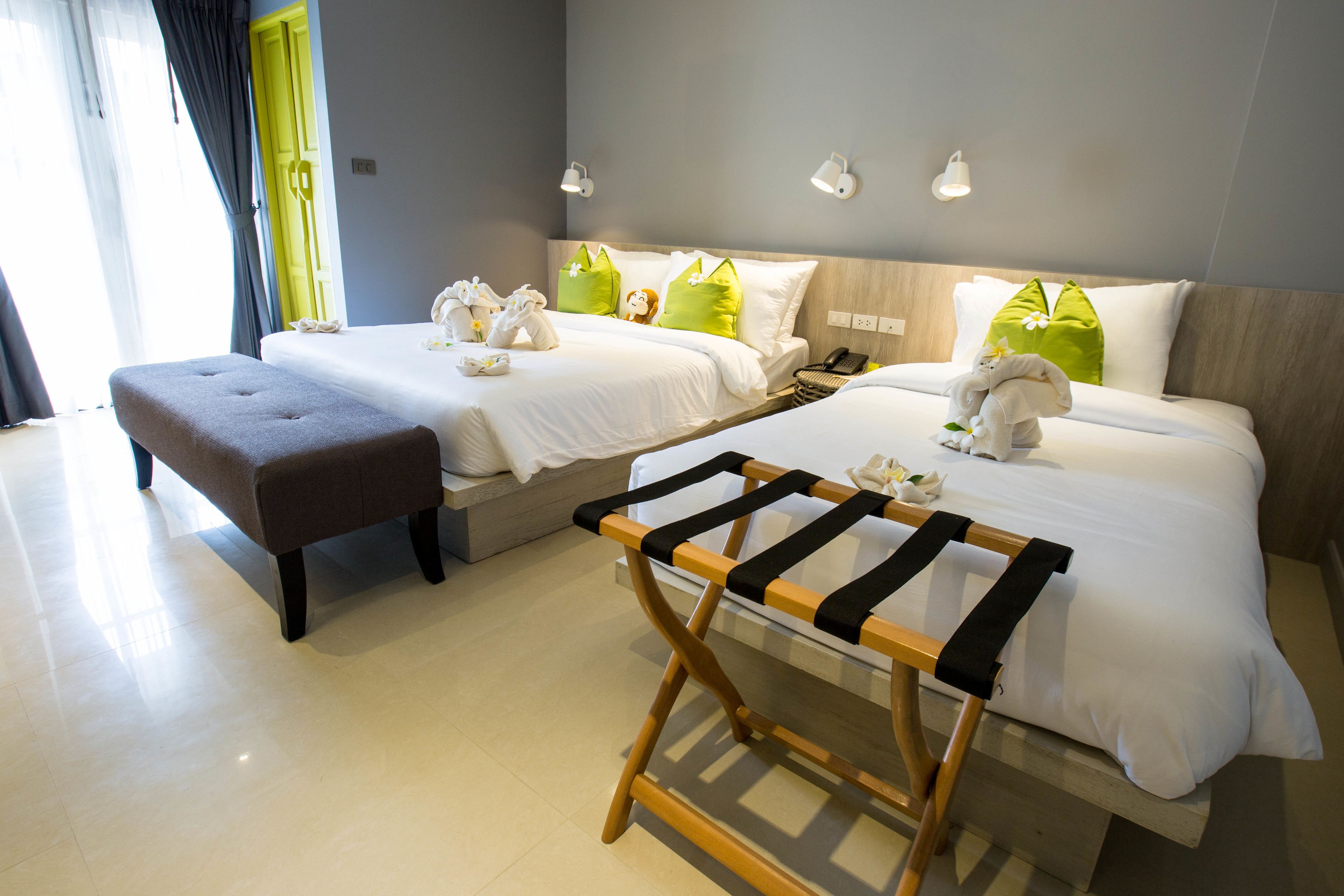 Une chambre d’hôtel avec deux lits, un banc et un porte-serviettes en bois.