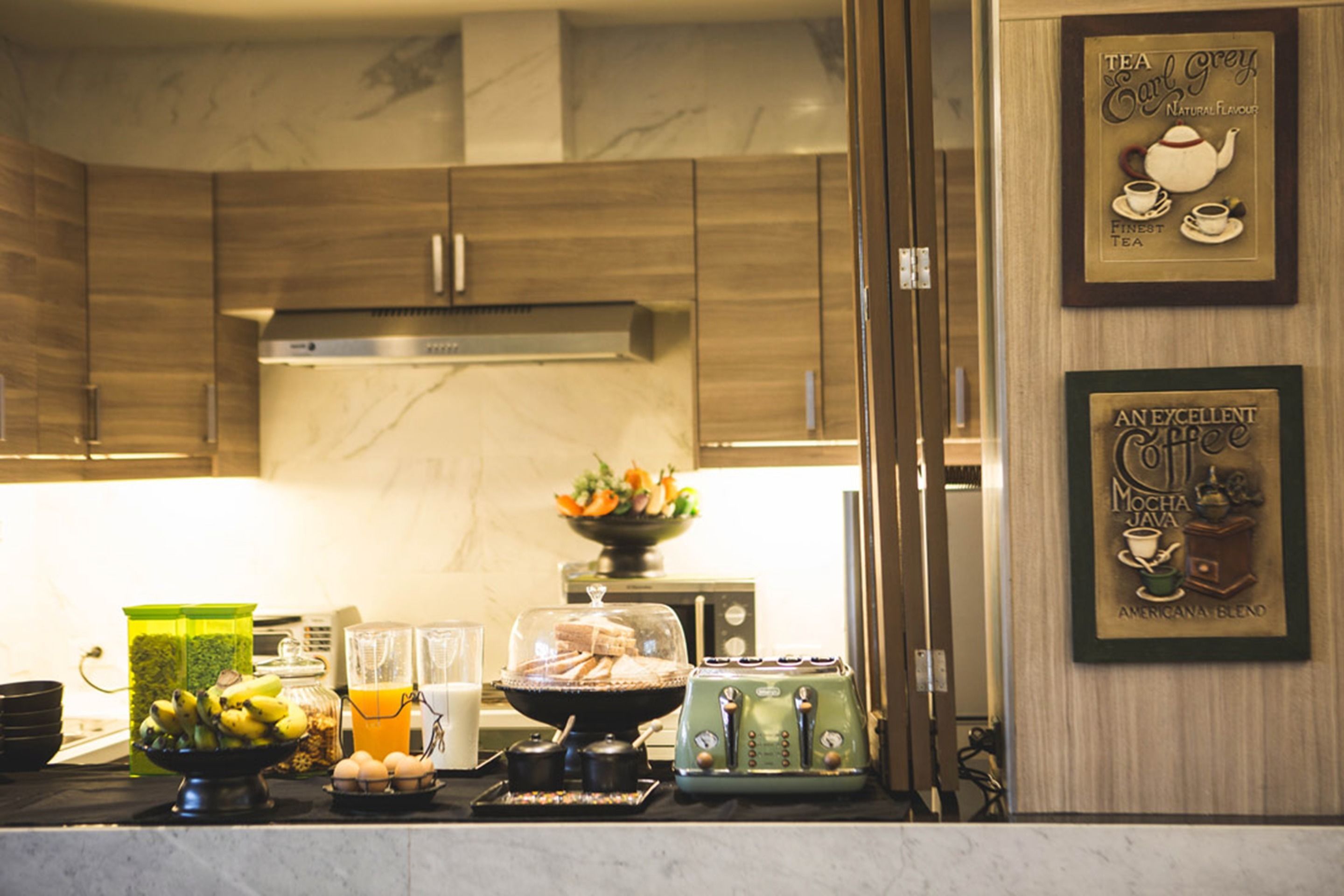 A kitchen with wooden cabinets, a stainless steel range hood, a fruit bowl, a toaster, and a coffee machine.