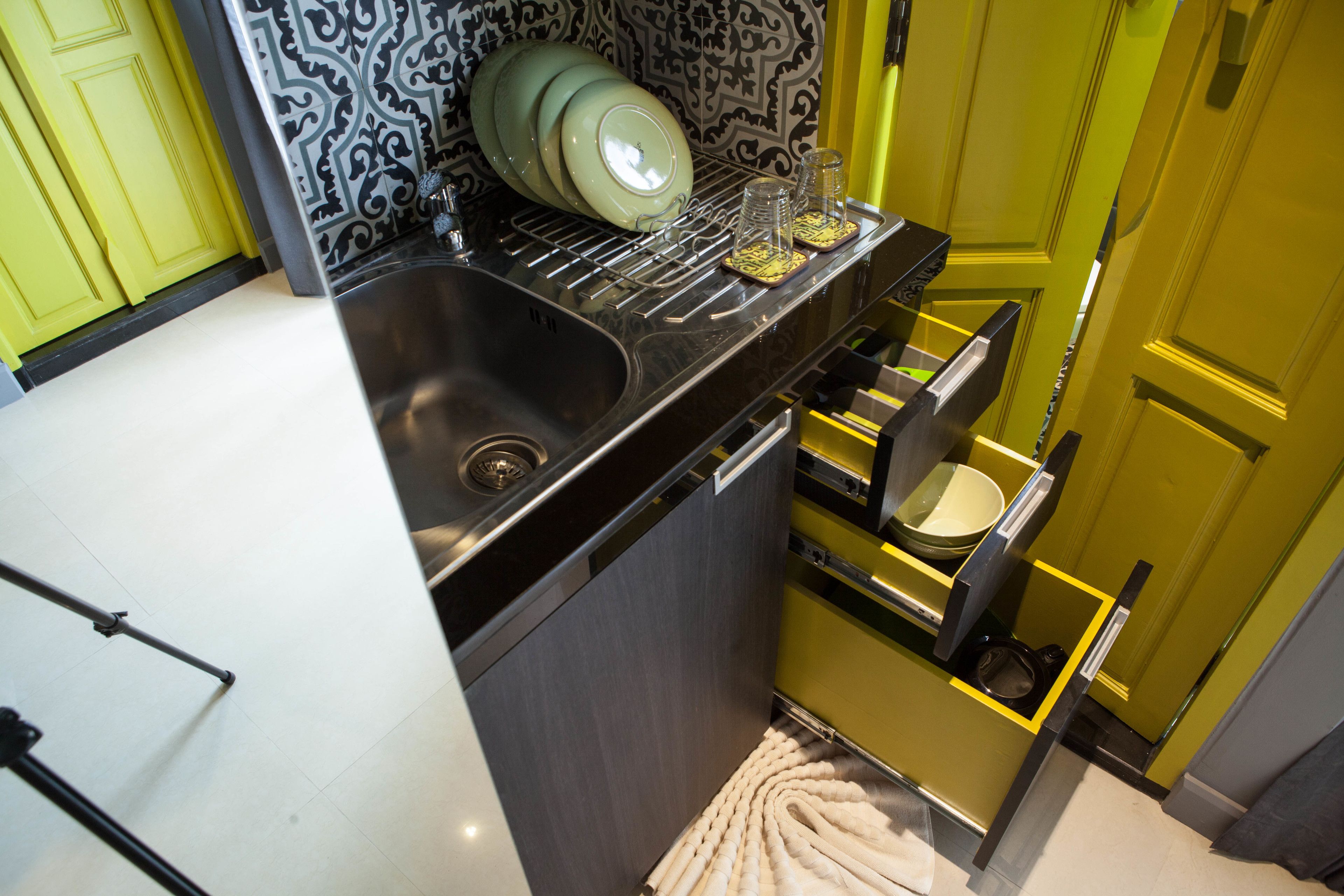A compact kitchen with a sink, a dish rack, and a built-in oven.