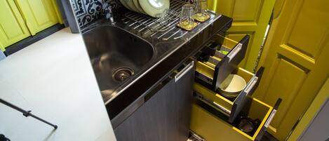A compact kitchen with a sink, a dish rack, and a built-in oven.