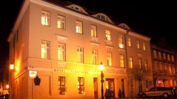 Monikerroksinen rakennus, jossa on valaistut ikkunat ja kyltti, jossa lukee: ”HOTEL SIEGIACKEI”.