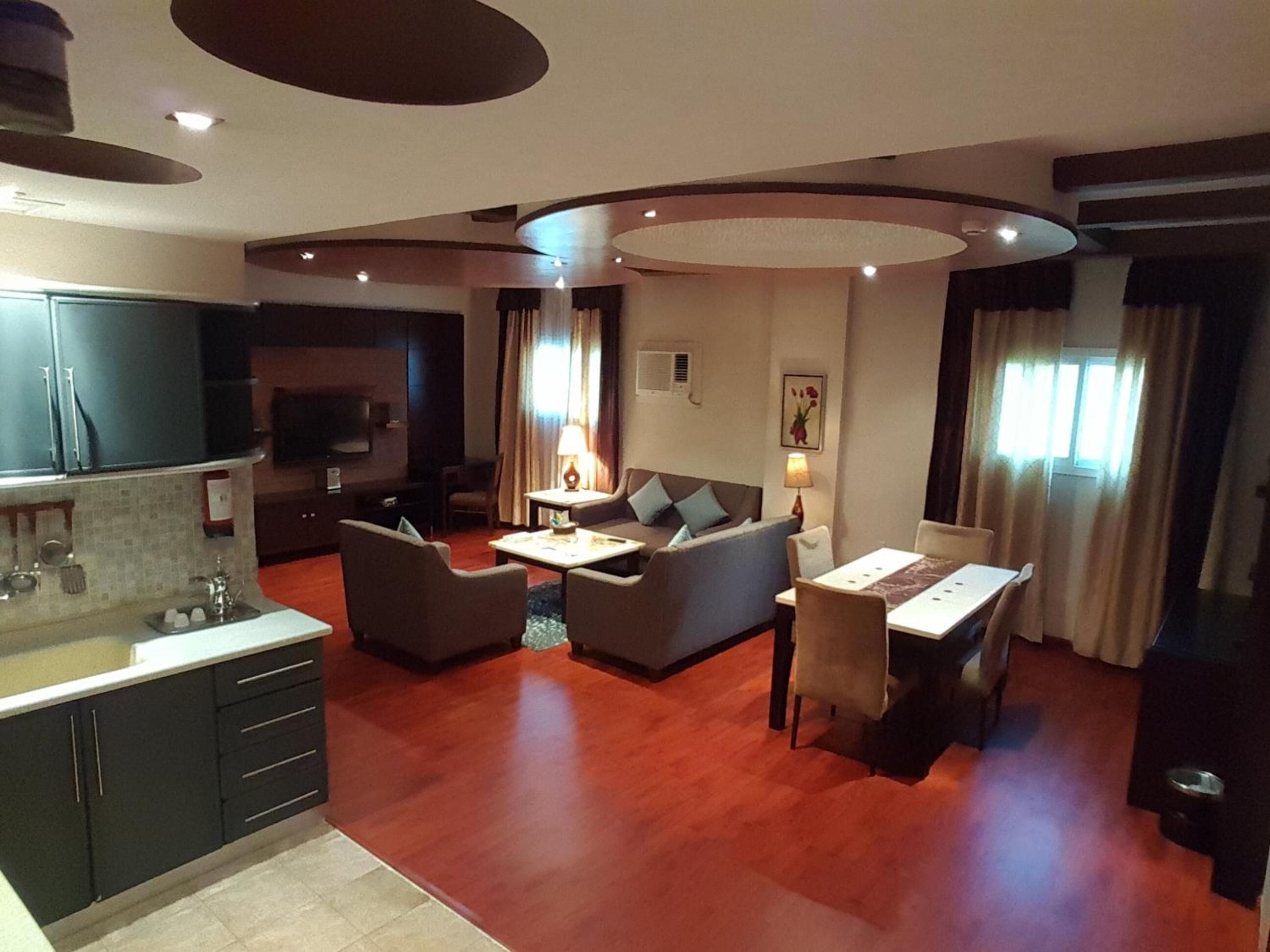 Una sala moderna con sofá, mesa de centro y mesa de comedor. Cuenta con una zona de cocina con armarios y un lavamanos.