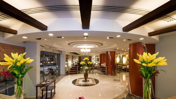 A hotel lobby with a central fountain, two vases of yellow flowers, and a reception desk. - Boudl Al Masif (Riyadh)
