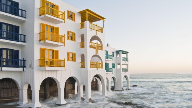 Un hotel sul lungomare con numerosi balconi, pareti esterne bianche e blu e vista sull'oceano.