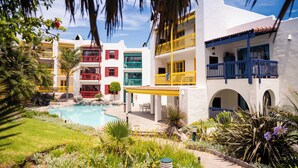 Un resort con piscina, diversi edifici colorati e una vegetazione rigogliosa.