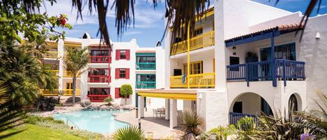A resort with a pool, multiple colorful buildings, and lush landscaping.