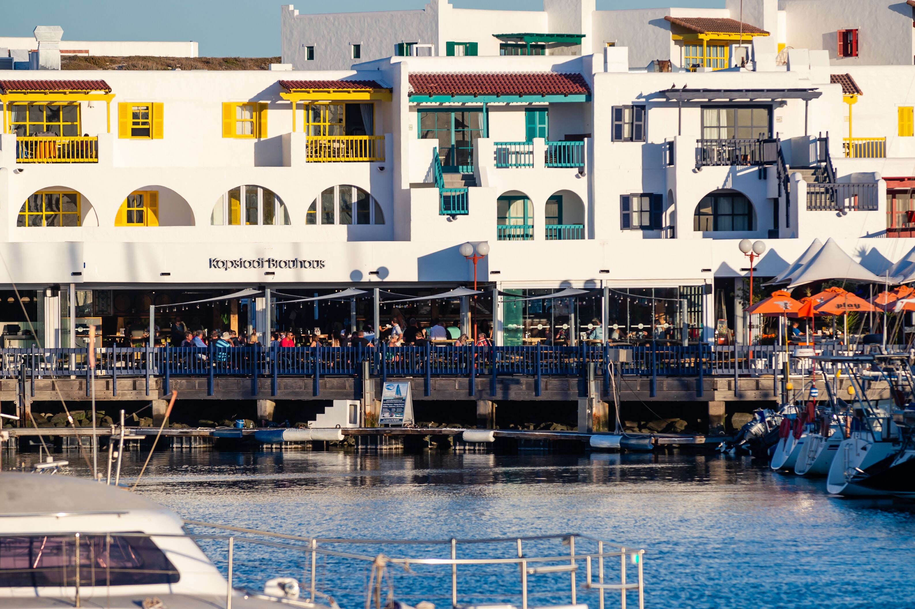 A waterfront building with balconies and a restaurant named "Kopstone Boutique."