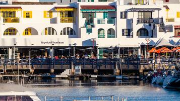 A waterfront building with balconies and a restaurant named "Kopstone Boutique."