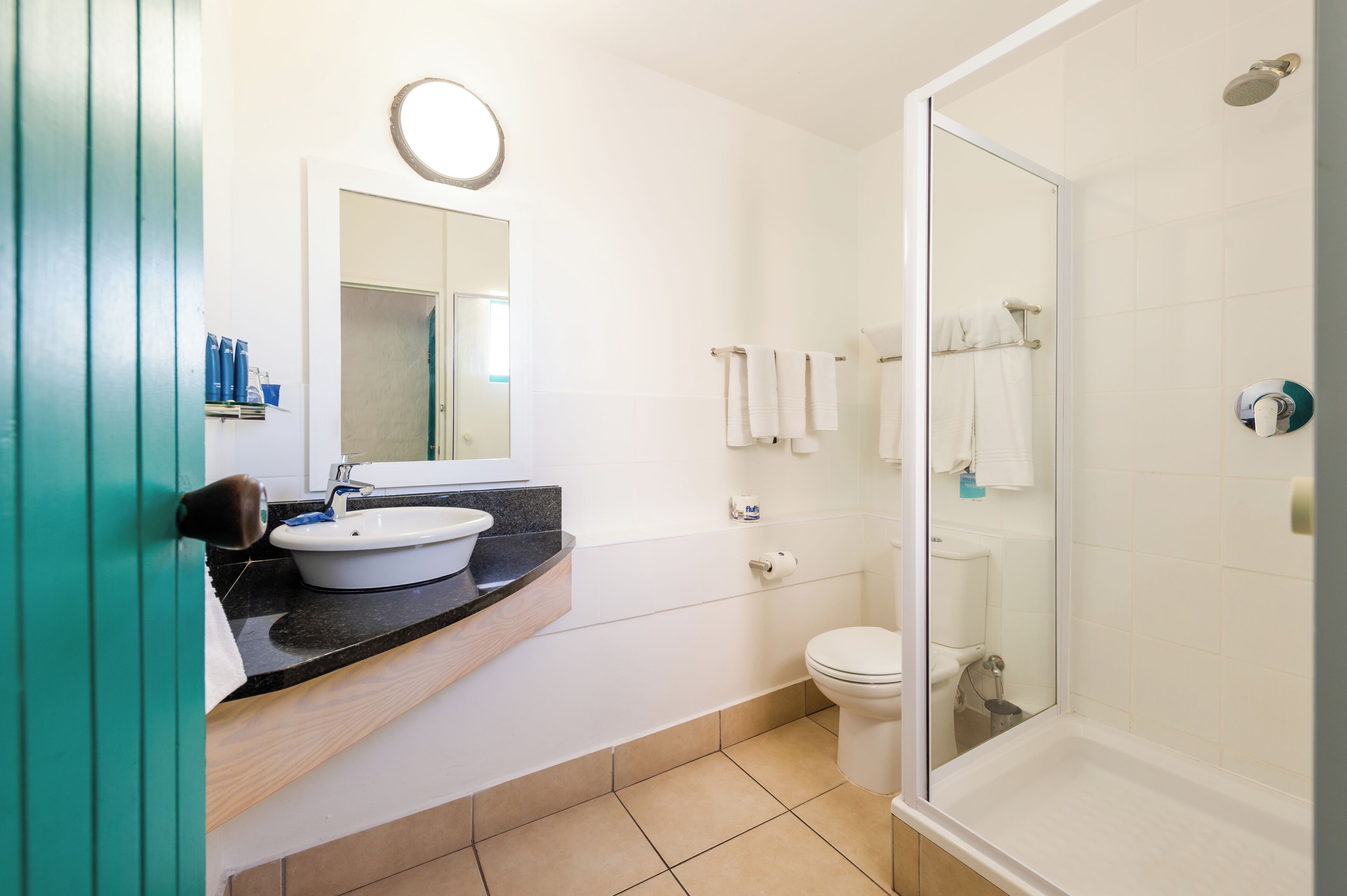 Et moderne badeværelse med vask, toilet og bruser.