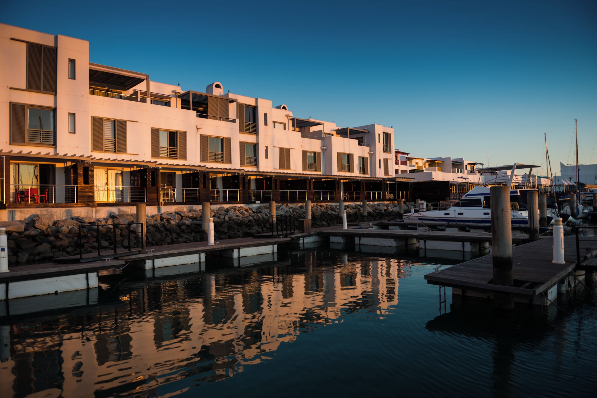 A marina with a row of buildings, some with balconies, and a boat docked.