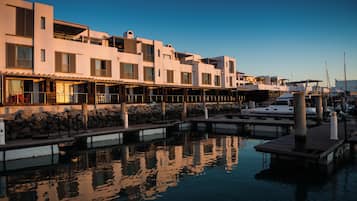 A marina with a row of buildings, some with balconies, and a boat docked.