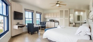 Habitación de hotel con cama, escritorio, silla, televisor y vista al mar.