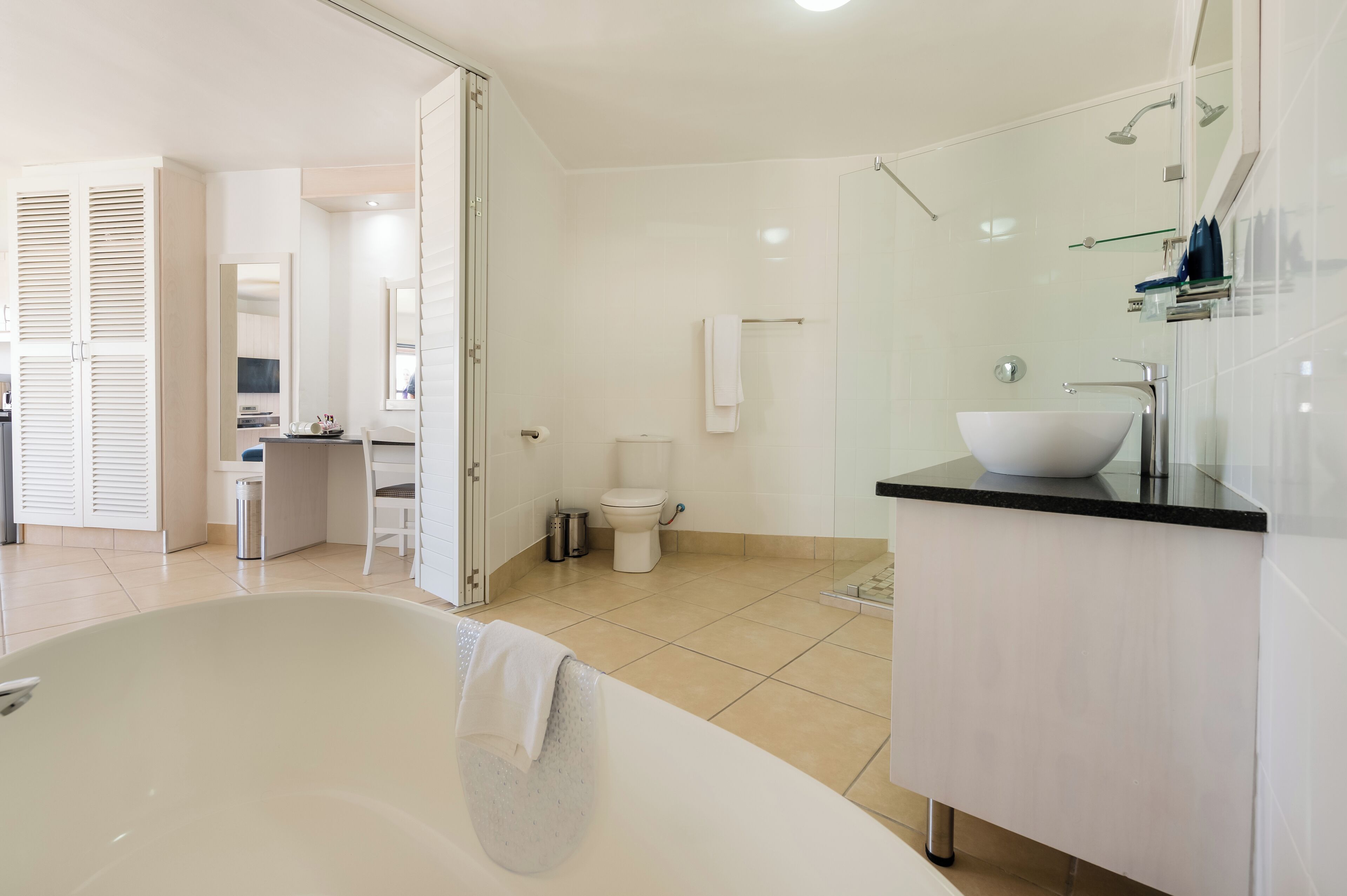 A modern bathroom with a freestanding bathtub, a glass-enclosed shower, and a white sink with a black countertop.