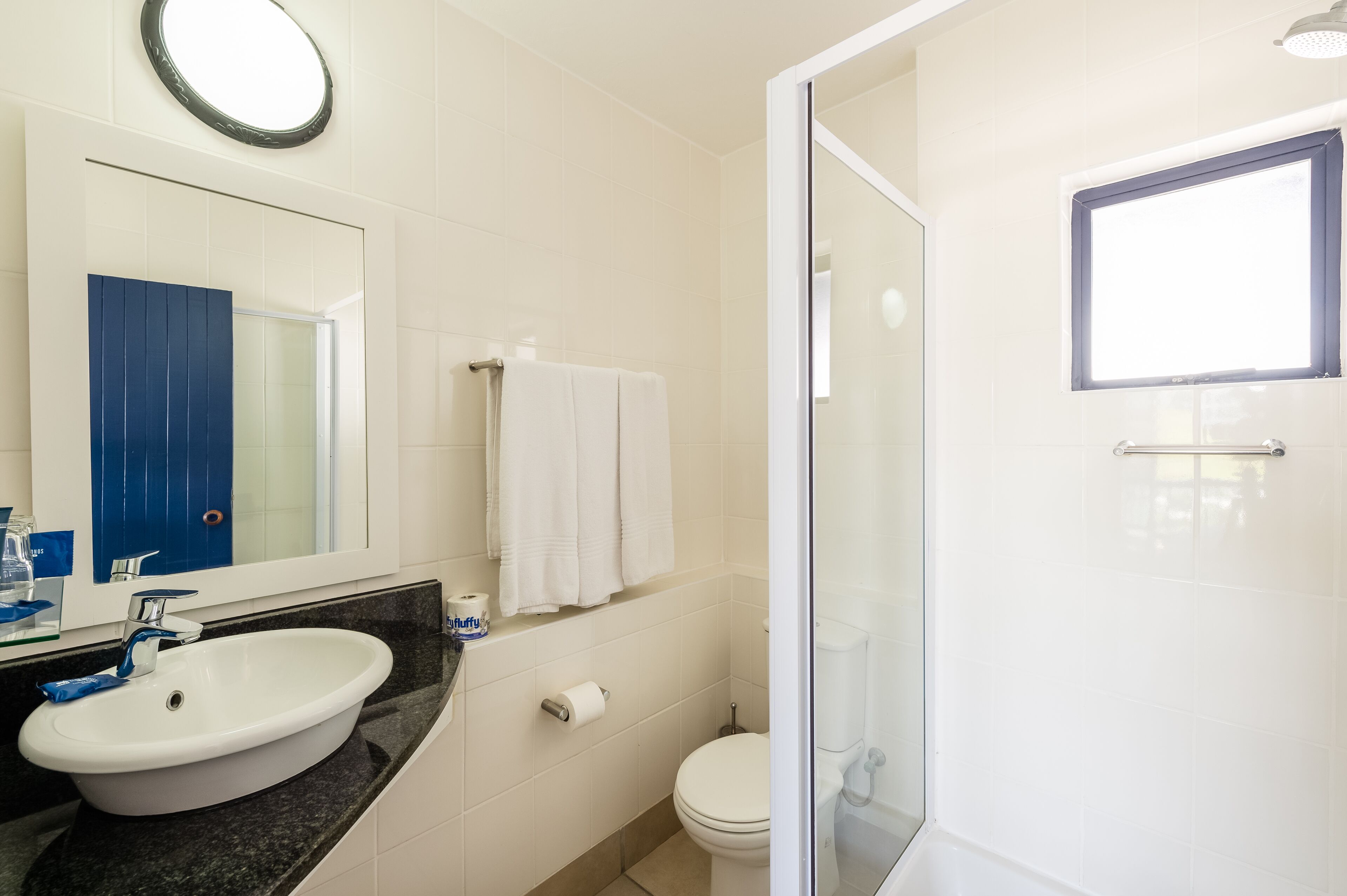 A modern bathroom with a white sink, mirror, and toilet.