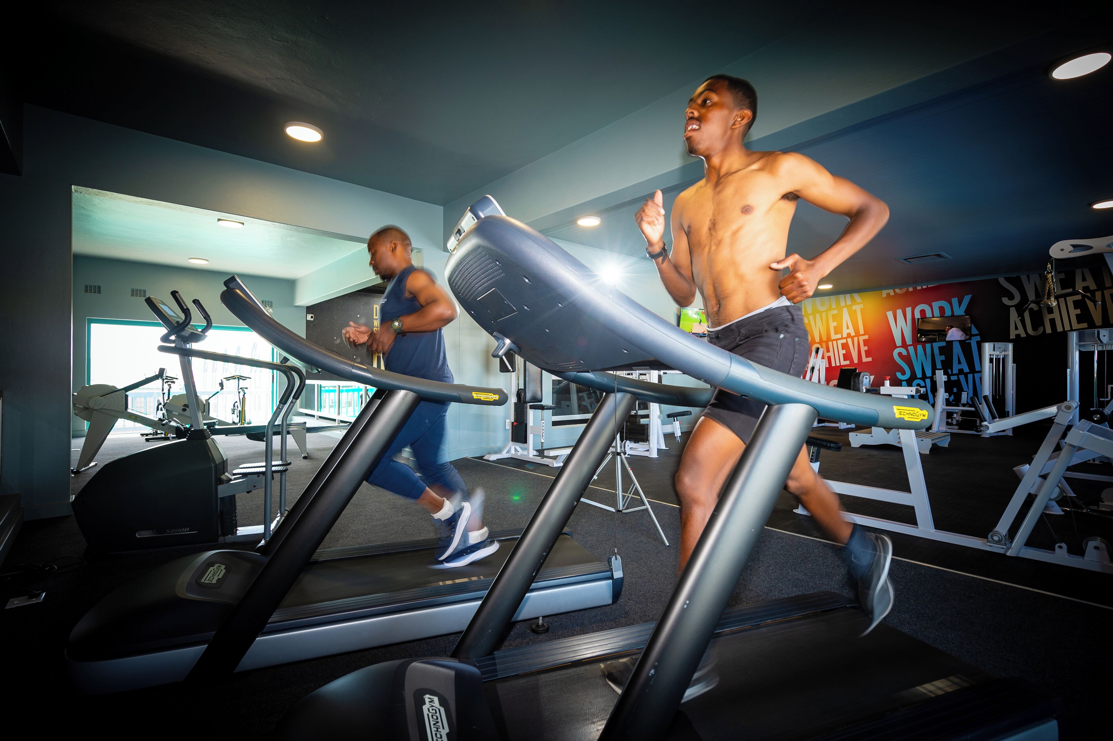 A gym with treadmills, weight machines, and a mirror reflecting the room.