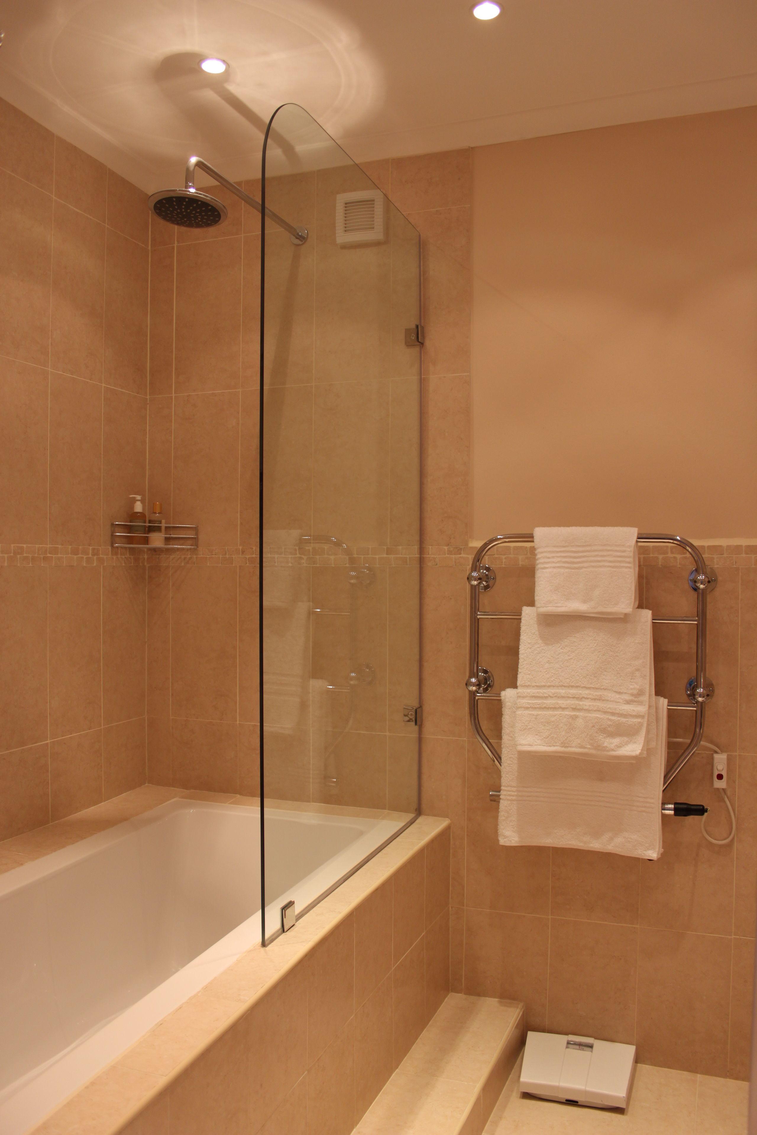 A modern bathroom with a glass-enclosed shower, a bathtub, and a towel rack with folded towels.