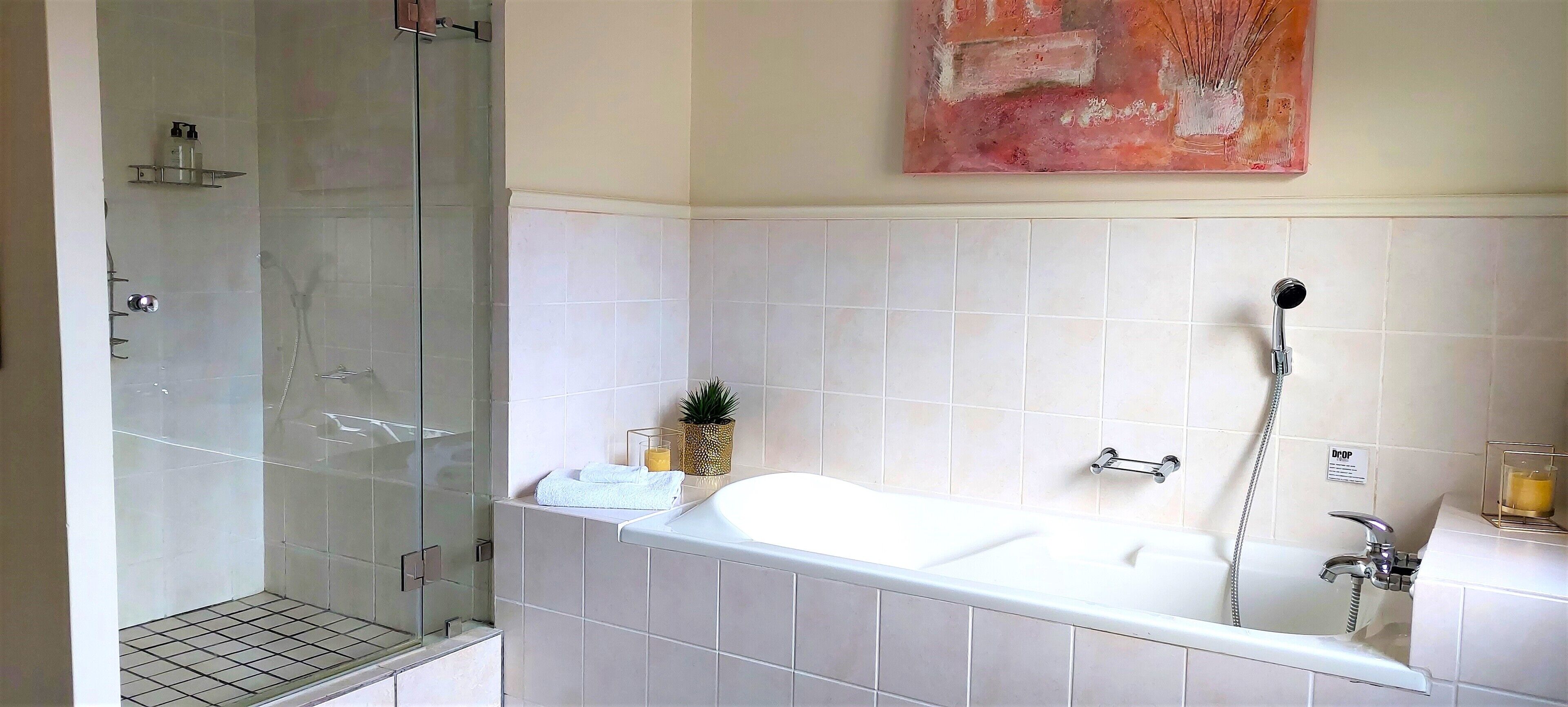 Un baño moderno con ducha de vidrio, una bañera grande y un lavamanos instalado en la pared.