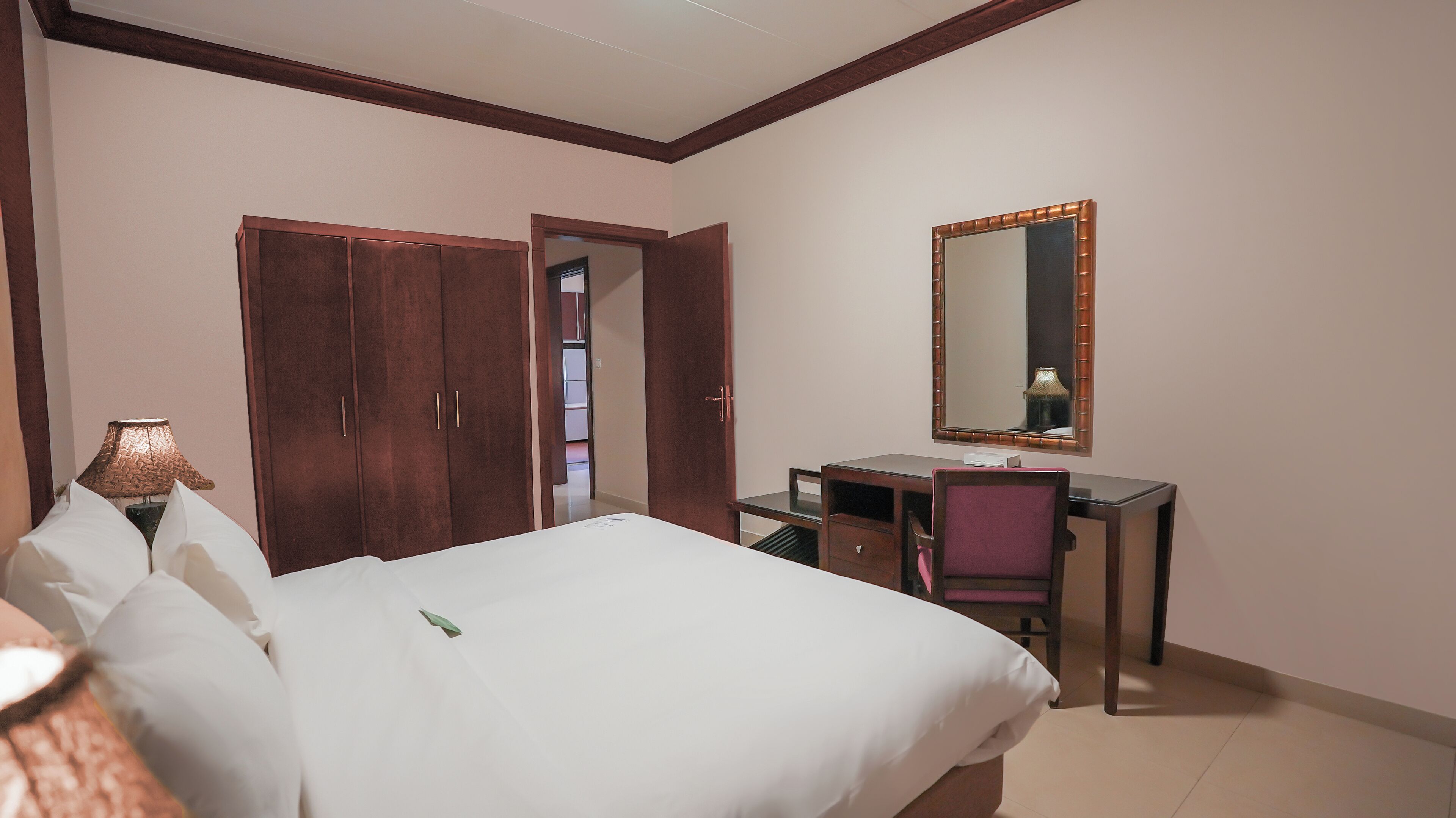Une chambre d’hôtel comprenant un lit, un bureau, une chaise, une armoire et un miroir.