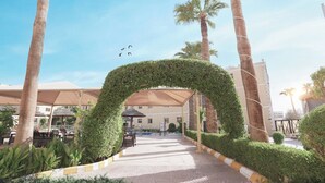 A pathway leading to a building with a covered outdoor seating area and palm trees. - Boudl Al Malaz (Riyadh)