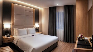 A hotel room with a large bed, bedside tables, a desk, and a view of the city through the window. - Boudl Al Malaz (Riyadh)