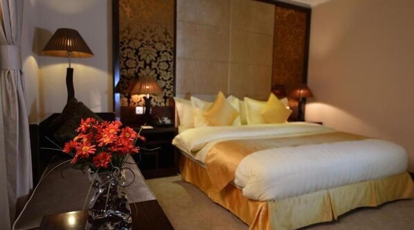 A hotel room with a bed, a nightstand, a lamp, and a vase with flowers.