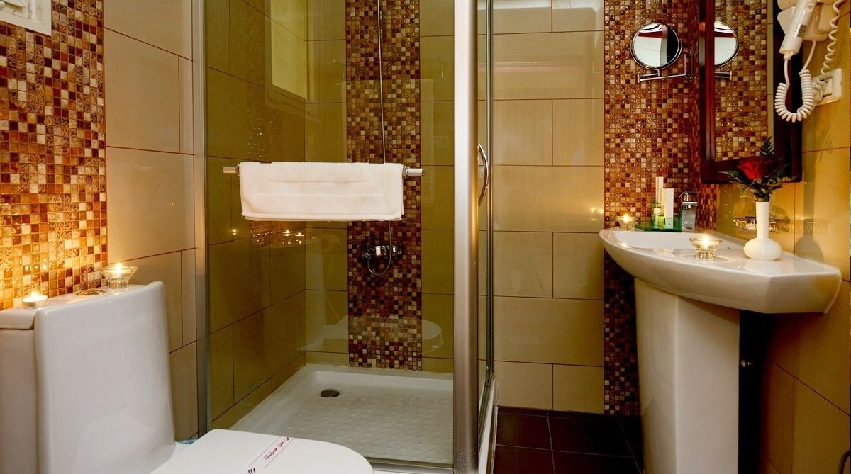 A bathroom with a glass shower enclosure, a white sink, and a tiled backsplash.