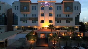 A hotel with a central entrance, multiple floors, and a parking area.