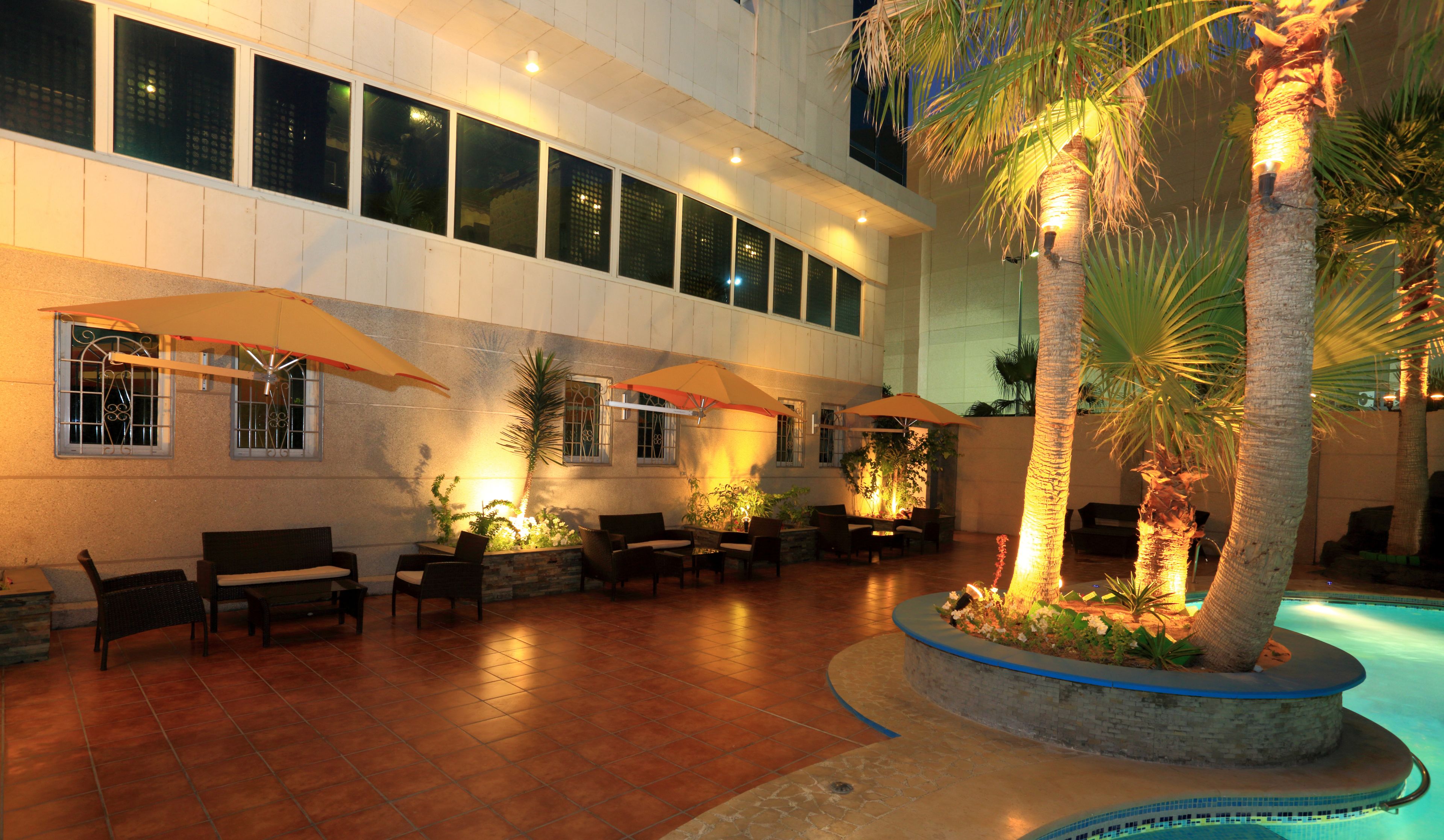 A spacious indoor courtyard with multiple seating areas, a central water feature, and large windows along the walls.