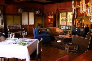 Un salon chaleureux avec un coin repas, un plancher en bois et une cheminée.