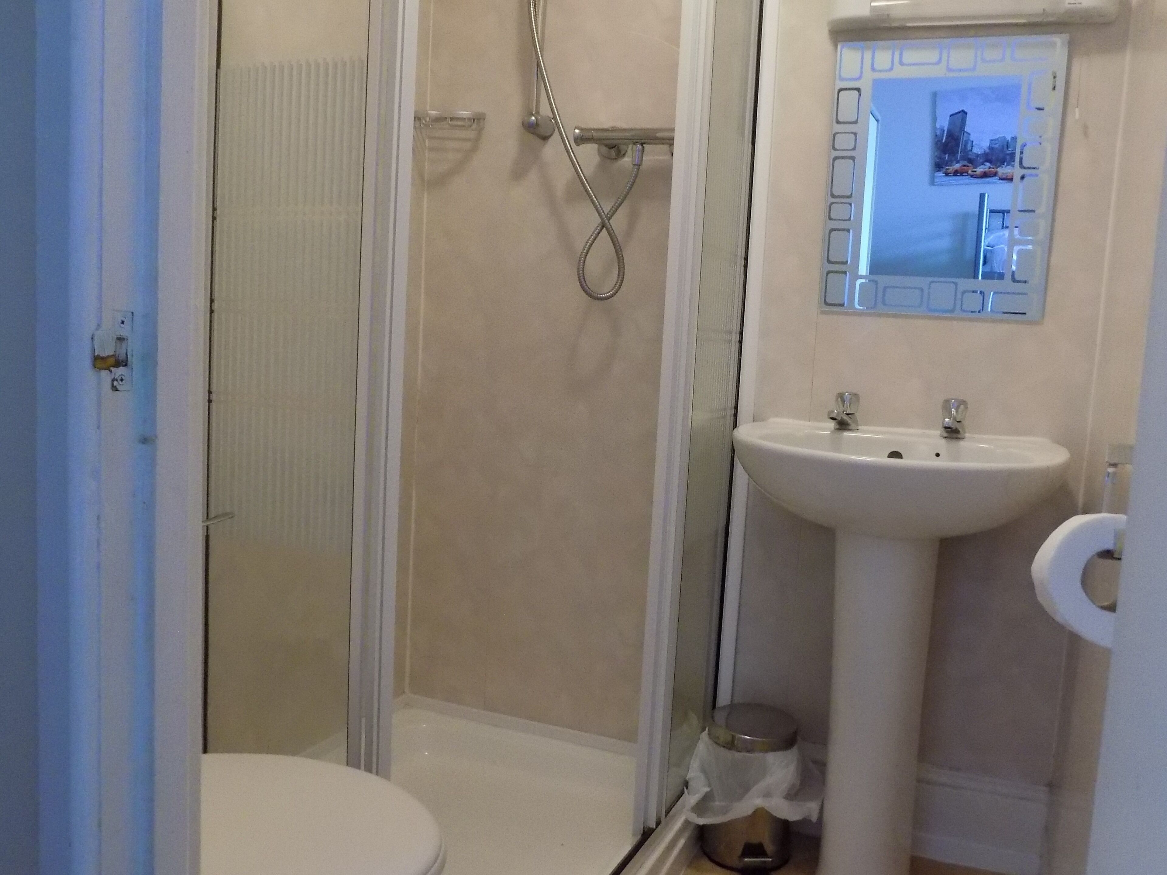 A bathroom with a toilet, a shower, and a sink.