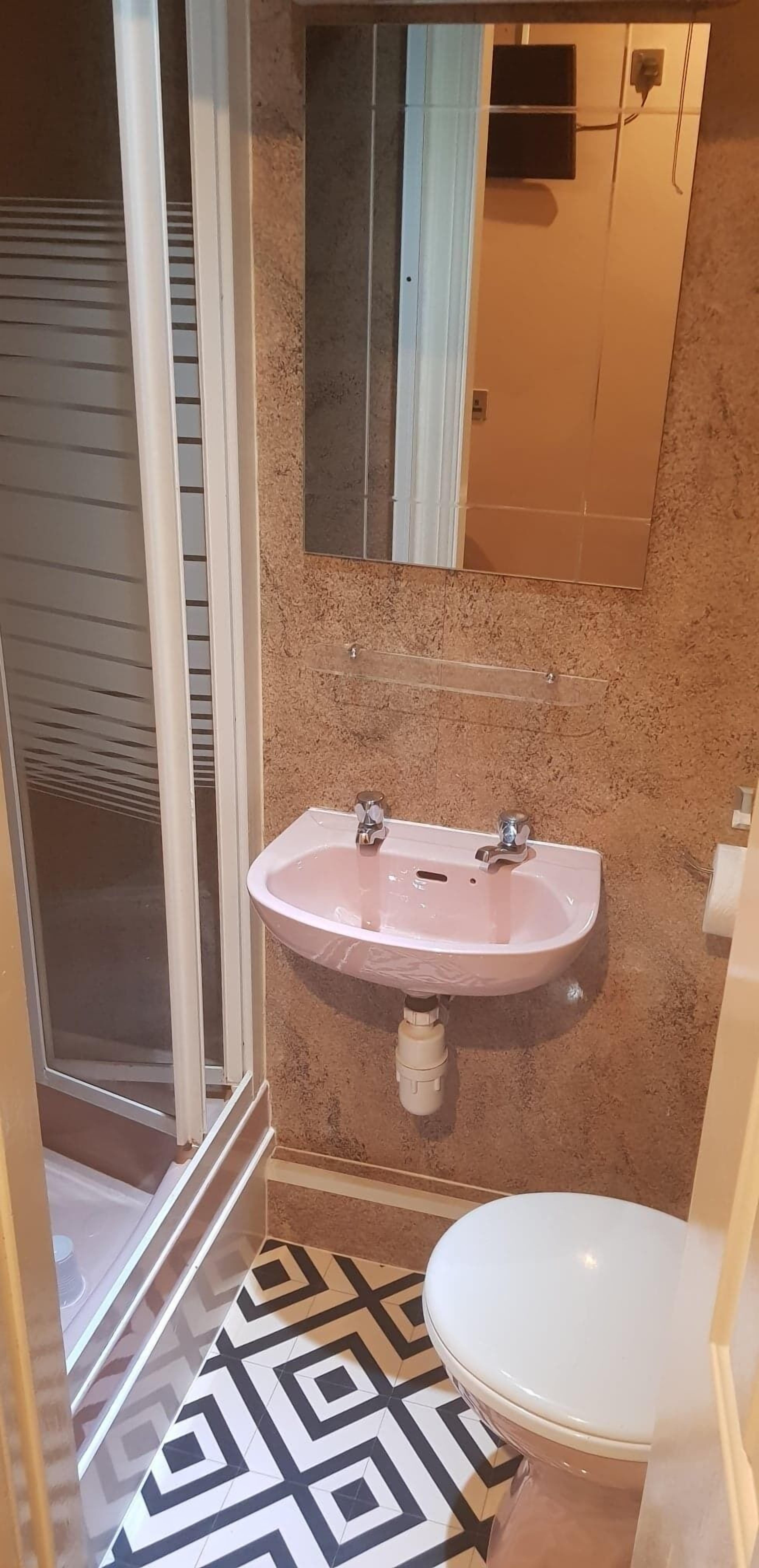 A bathroom with a white sink, a toilet, and a shower area.