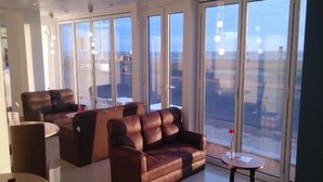 A spacious living area with leather sofas, a round coffee table, and large windows offering a view of the city. - The New Royal Windsor Hotel (Blackpool)