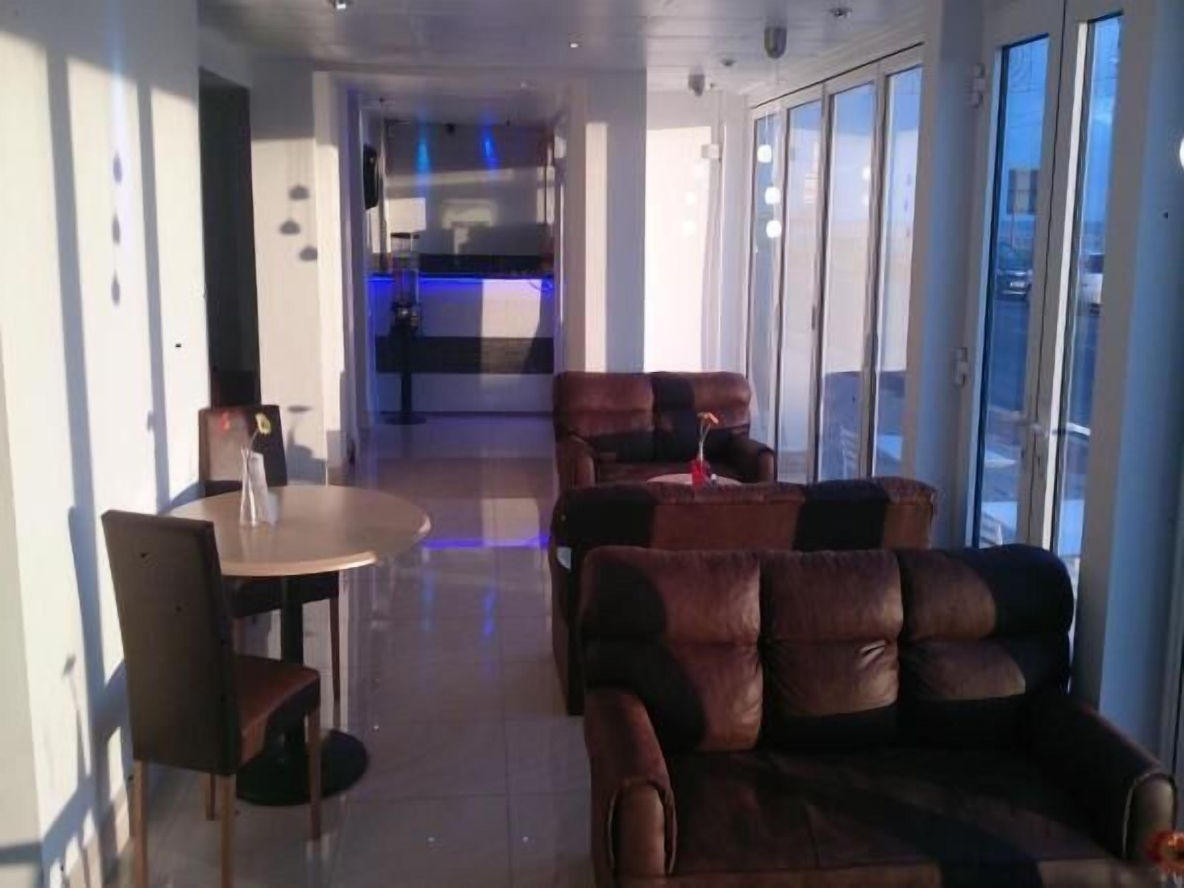 A modern interior with a dining area, leather sofas, and large windows.