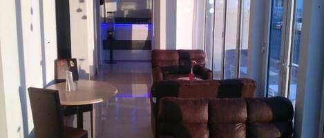 A modern interior with a dining area, leather sofas, and large windows.