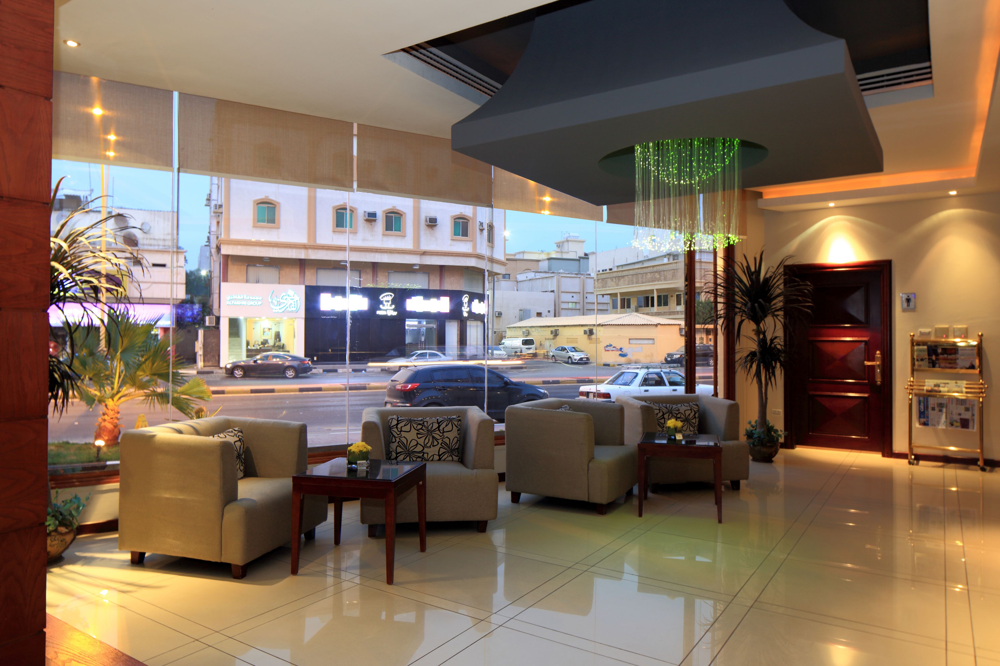 A hotel lobby with sofas, a reception desk, and a view of the street outside.