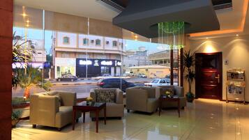 A hotel lobby with sofas, a reception desk, and a view of the street outside.