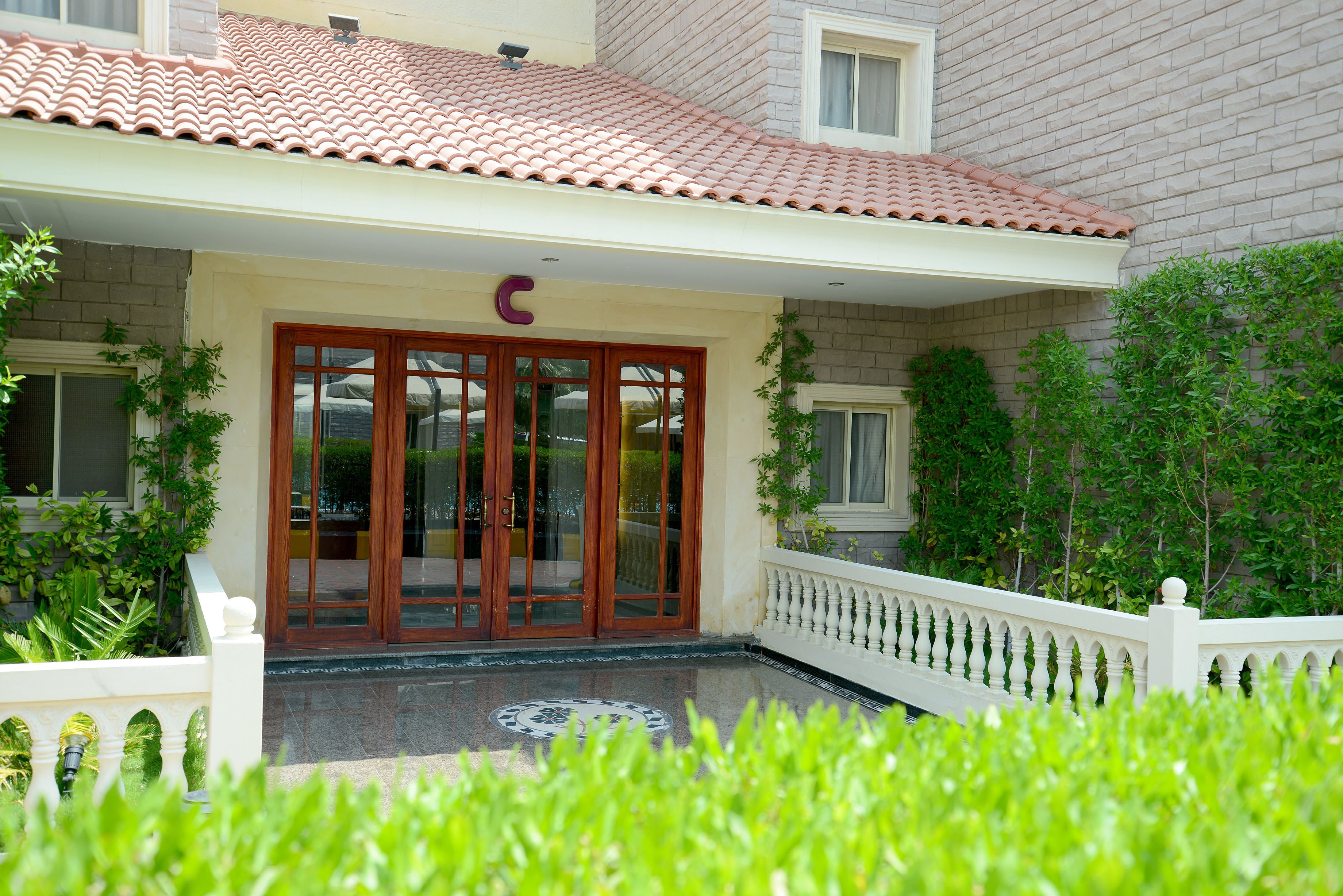A building with a tiled roof, a gated entrance with glass doors, and a white railing.